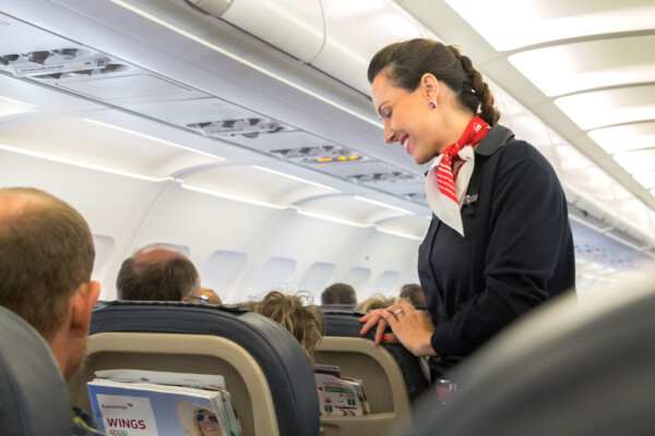 A female flight attendant is speaking with a passenger sitting in the economy class on Eurowings Airline.