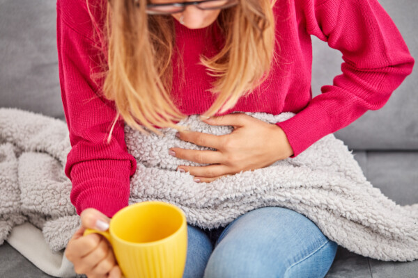 A woman with a stomach ache drinking tea