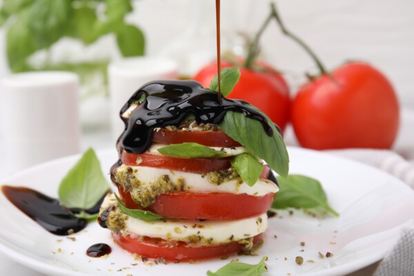 Balsamic vinegar being poured onto a Caprese salad