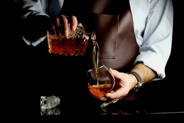 A bartender pouring brandy into a glass