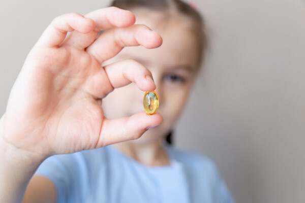 child holding vitamin d supplement