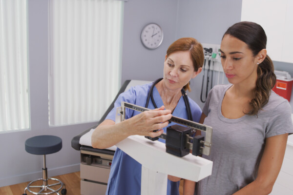 nurse weighing female patient