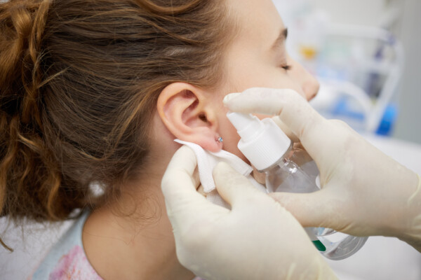 Someone spraying a new piercing