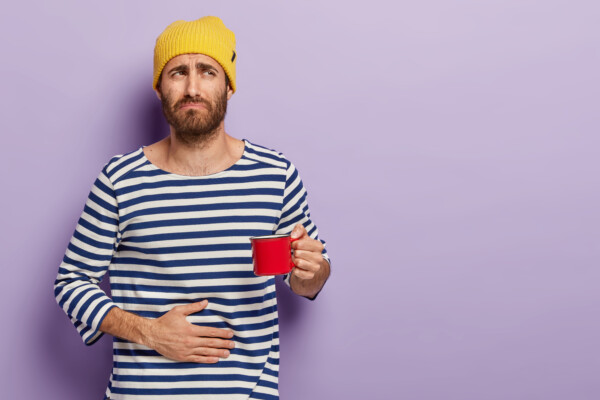 A man with stomach pain drinking tea