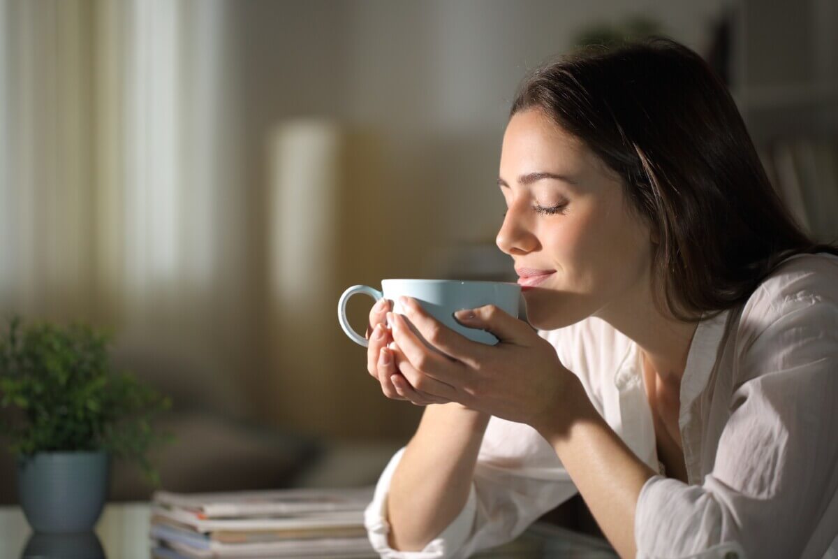 A woman smiling as she drinks tea