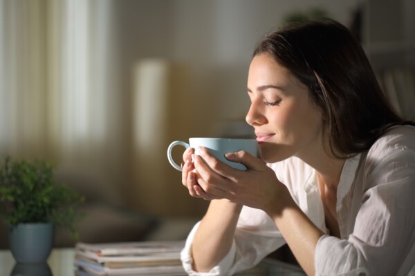 A woman smiling as she drinks tea