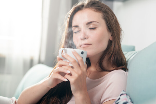 A woman drinking a steaming cup of tea