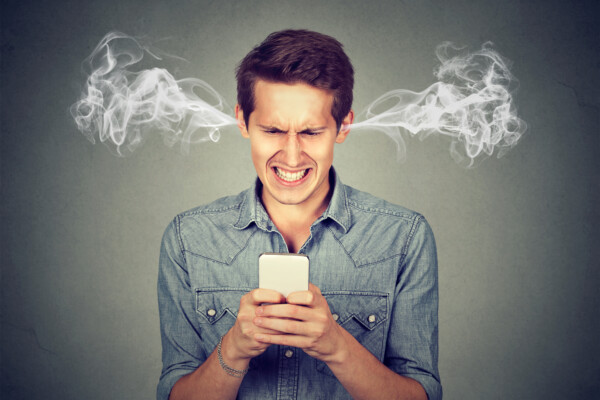 Angry man texting or using social media on smartphone