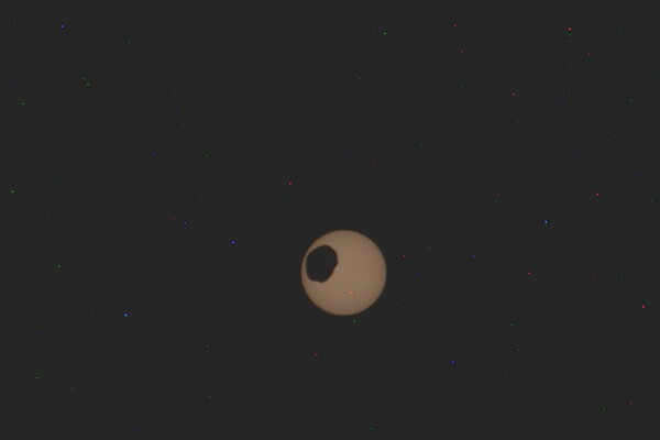 The potato-shaped Mars moon of Phobos transits from top to bottom left across the Sun