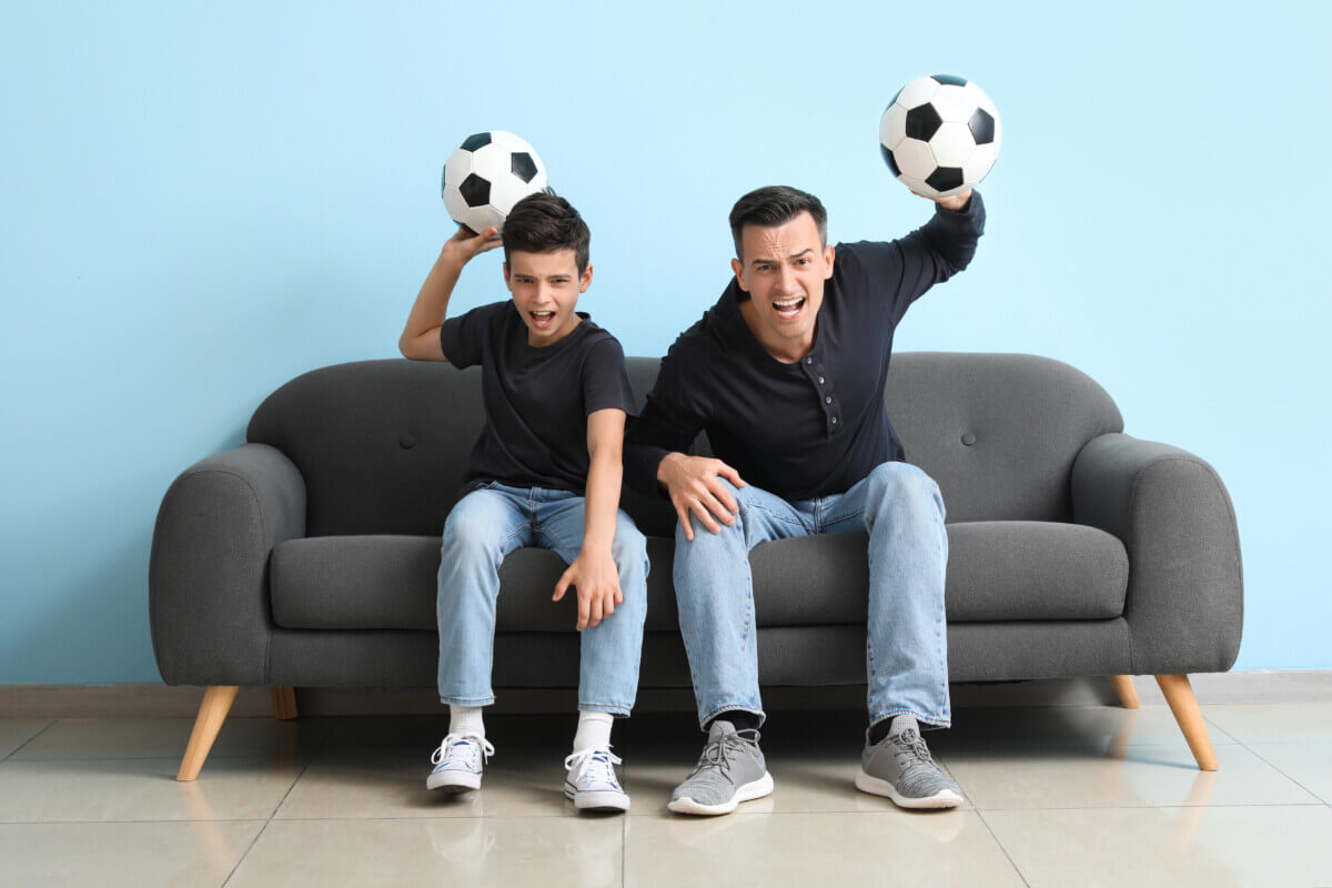 Angry boy with angry dad watching soccer