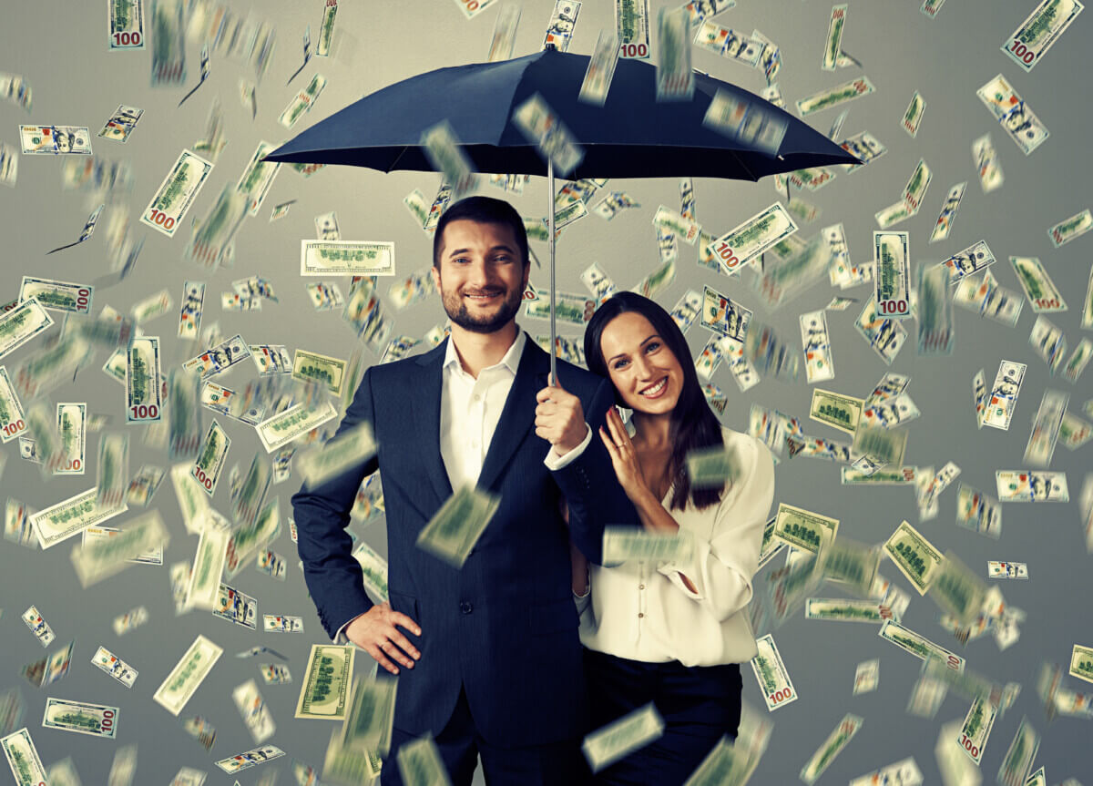 couple with umbrella standing under money rain