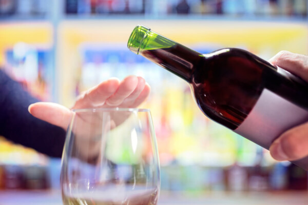 Woman's hand rejecting more alcohol from wine bottle