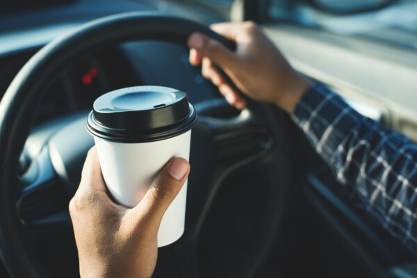Man holding coffee paper cup in car