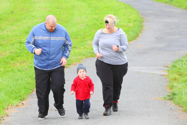 Overweight parents with her son running together.
