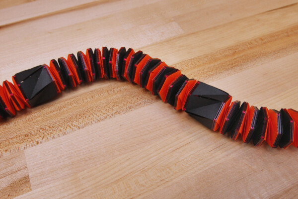 The robot is made of segments that can fold into a flat disk and extend into a cylinder. Partial folds bend the robot and allow for motion and steering.