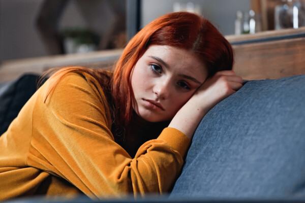Sad teen girl laying on a couch alone