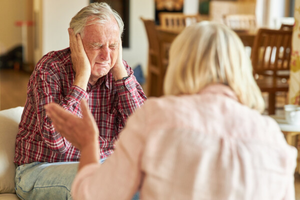 Senior man covers his ears during an argument with another senior