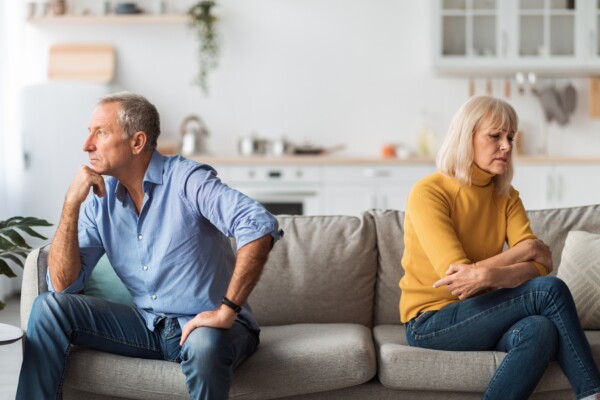 Unhappy couple in fight or argument sitting apart on a couch
