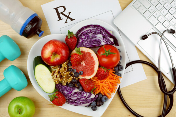 Prescription for good health overhead with stethoscope, healthy fresh food and exercise equipment.