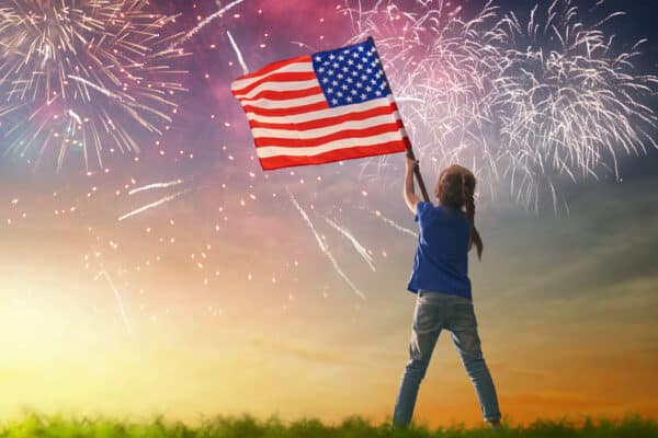 Young girl waving American flag to celebrate Independence Day on July 4th