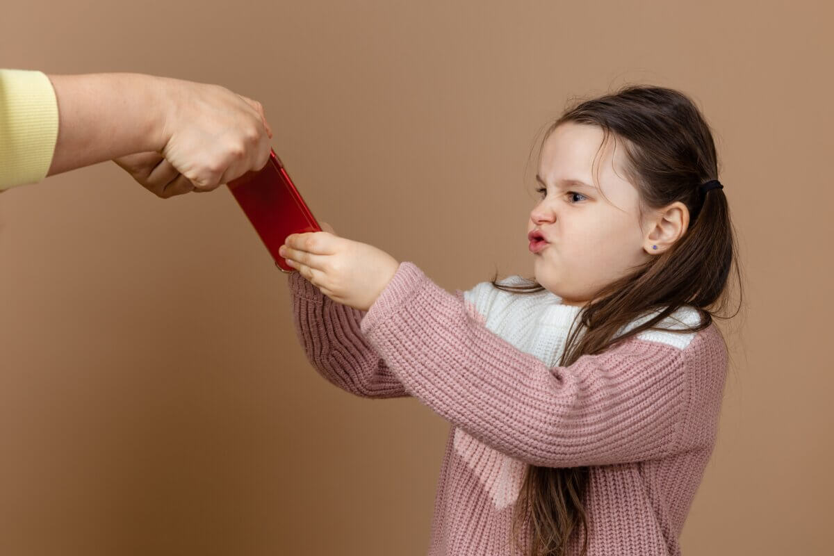 Angry little girl fighting with parent over smartphone