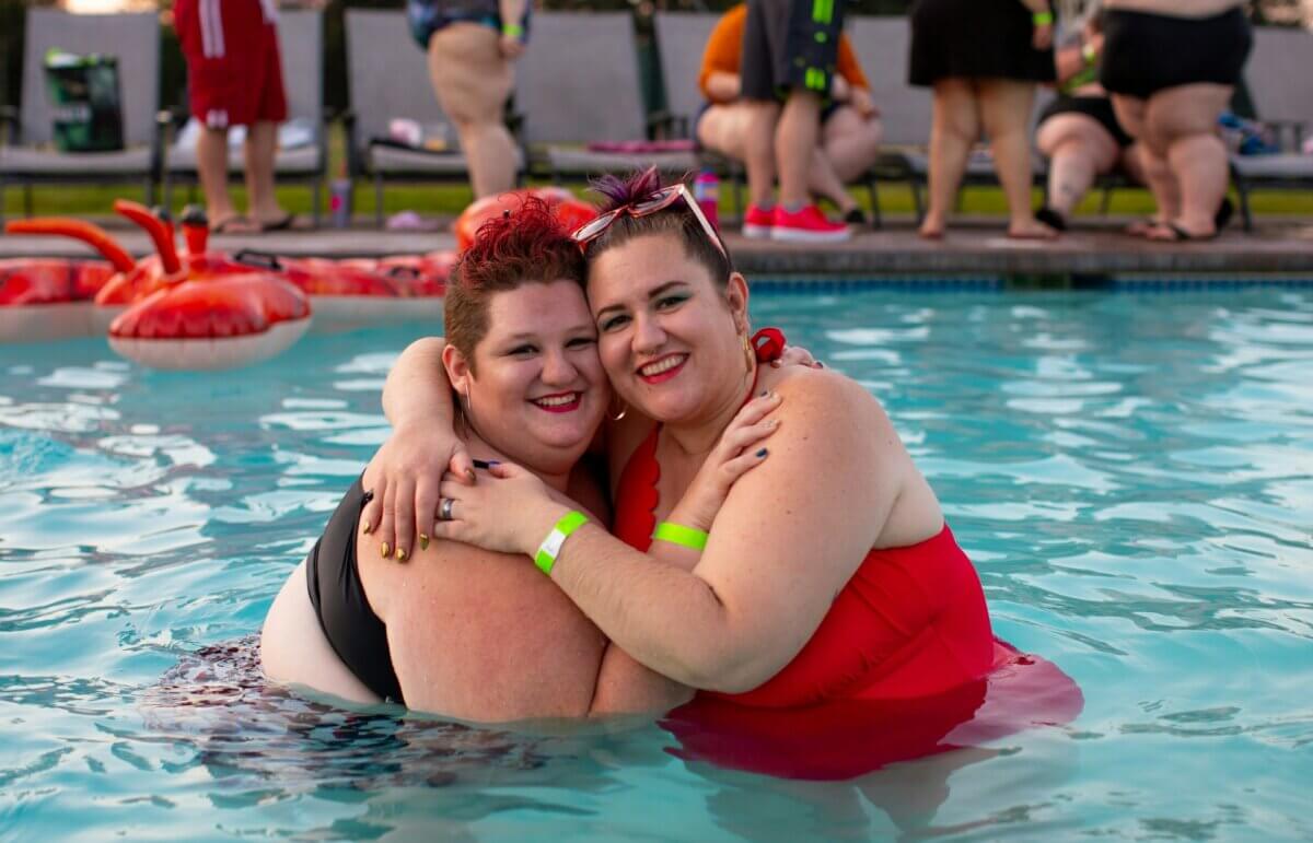 Women with obesity hugging in a pool