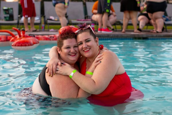 Women with obesity hugging in a pool