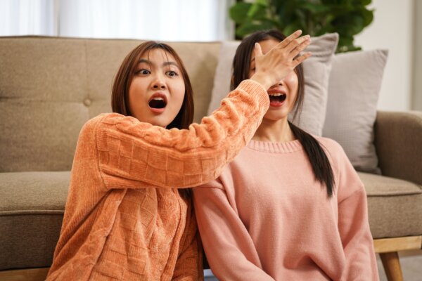 Young woman covering eyes of girlfriend