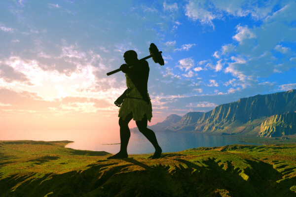 Primitive man silhouette against the sun.