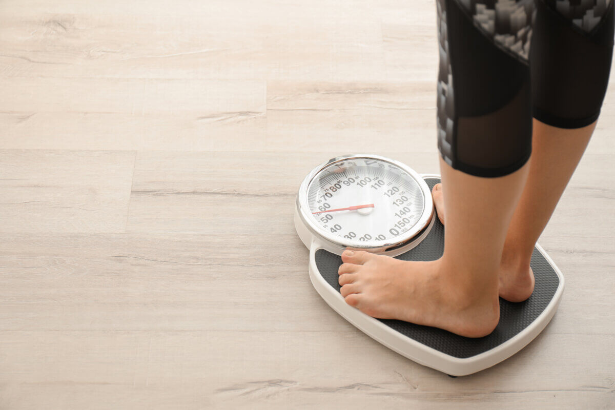 Woman measuring her weight using scale