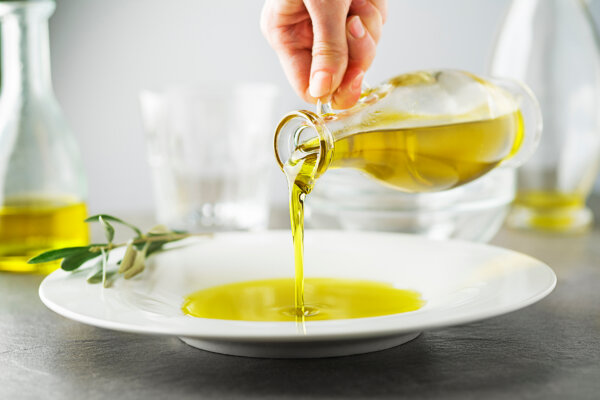 Bottle of extra virgin olive oil pouring to plate