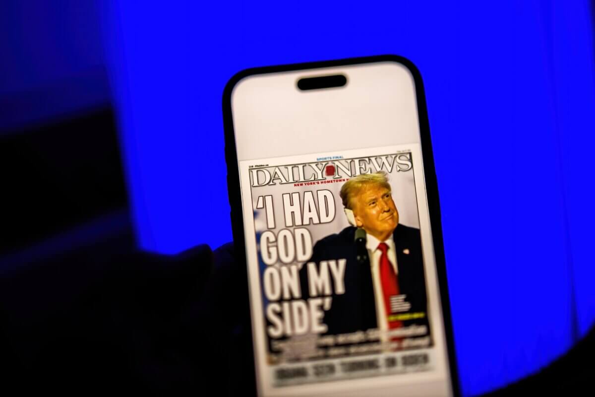 Man reading the Daily News newspaper with a cover featuring Donald Trump and the headline I Had God on My Side after an assassination attempt