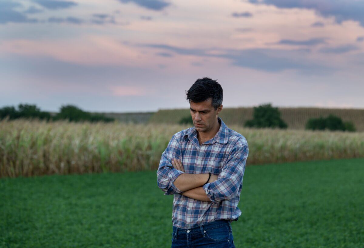 Worried and concerned rural man standing in field