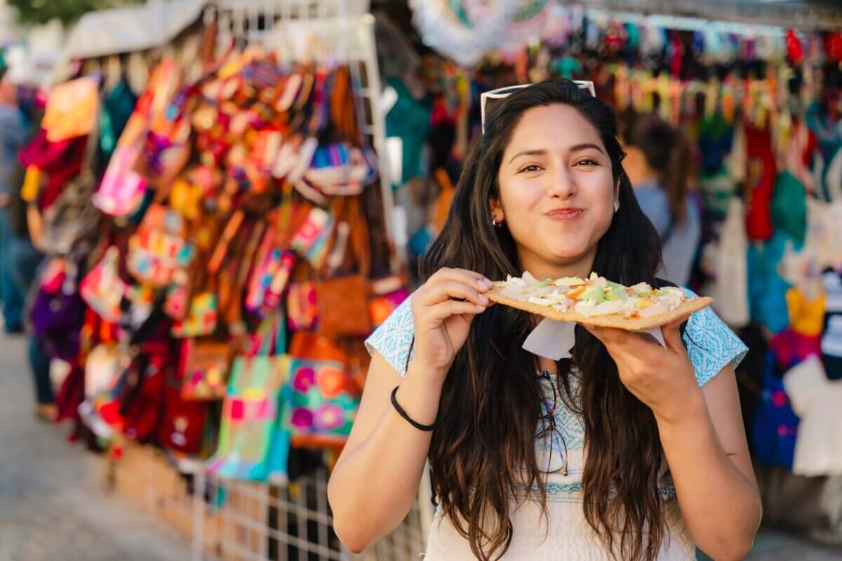 Young Latina woman eating chicharron preparado in a market in Oaxaca, Mexico