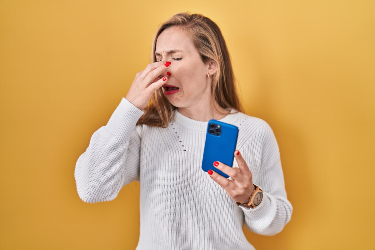 woman using smartphone typing message smelling something stinky