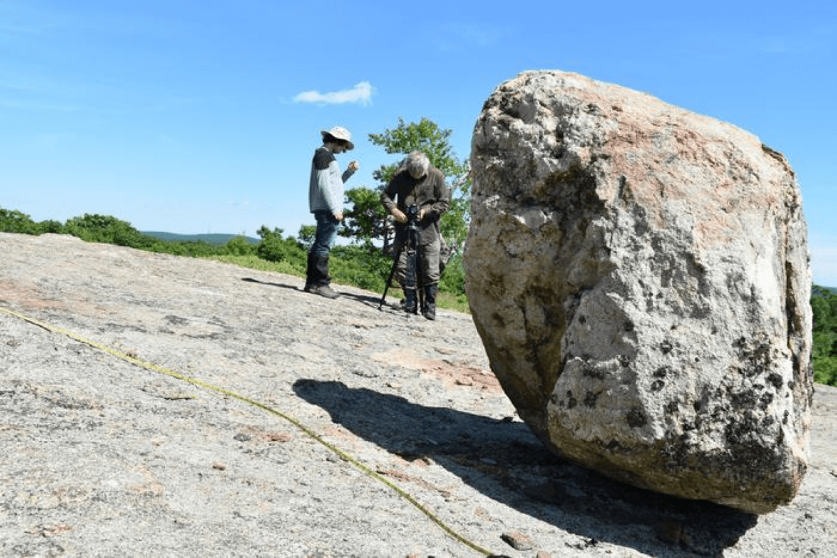 In New York’s Harriman State Park, geologist William Menke (right) and a student study a precariously balanced boulder that has remained in position for the last 15,000-plus years. It could hold clues to the maximum size of earthquakes over that period. 