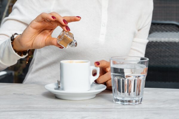 woman adds cinnamon powder to her coffee