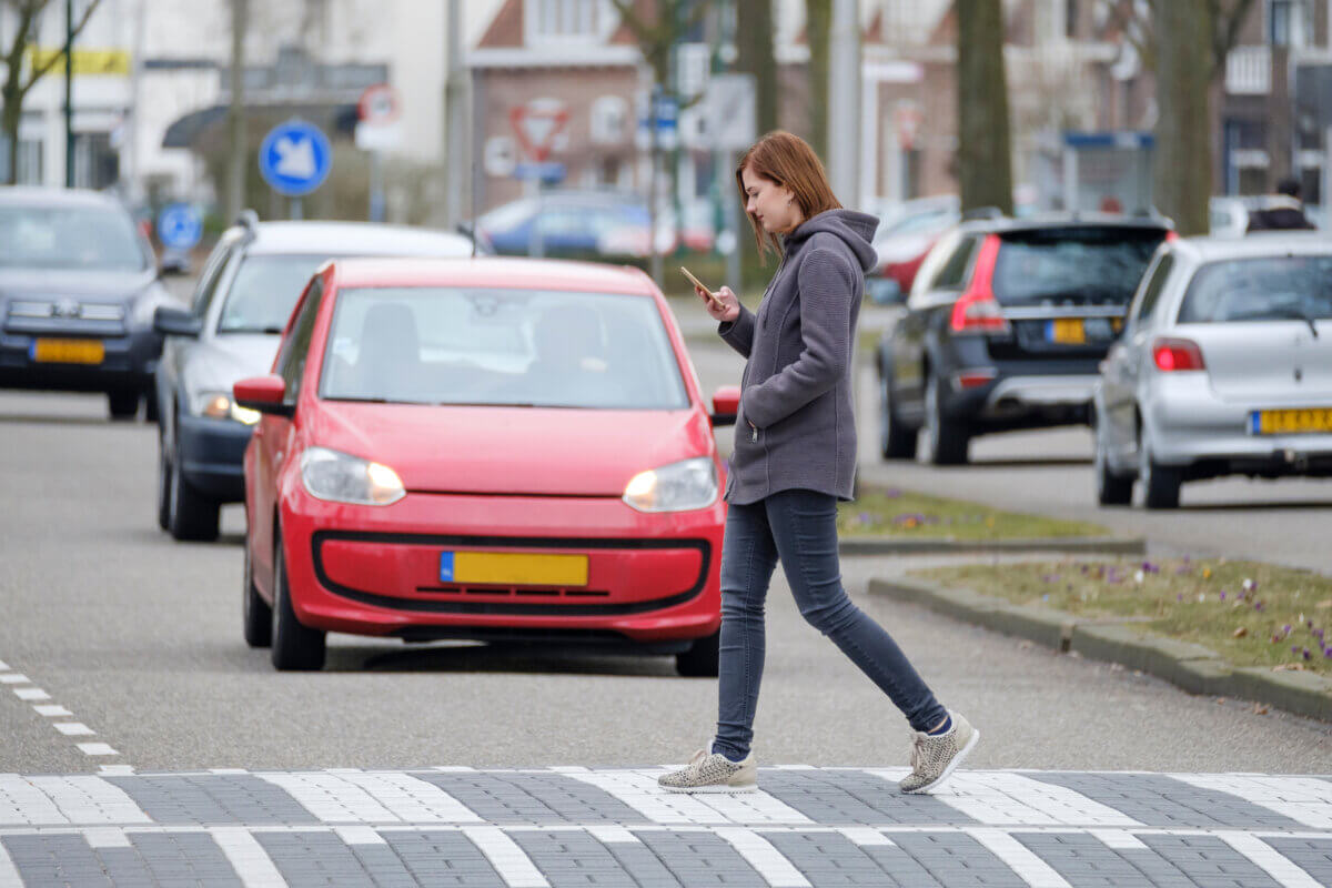 Woman walks on the crosswalk and checks her smartphone for messages and does not pay any attention to traffic.