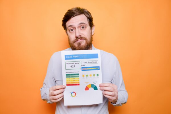 Worried man holding poor credit score report
