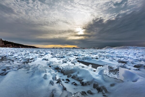The beginning of the ice age on the Ob River with snow and ice hummocks off the coast. Berdsk, Novosibirsk region, Western Siberia of Russia