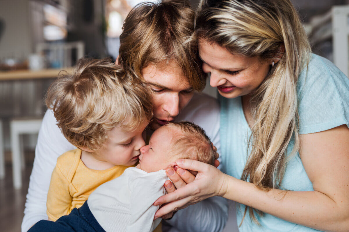 Family kissing newborn baby