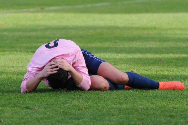 A soccer player holds his head in pain after suffering an injury