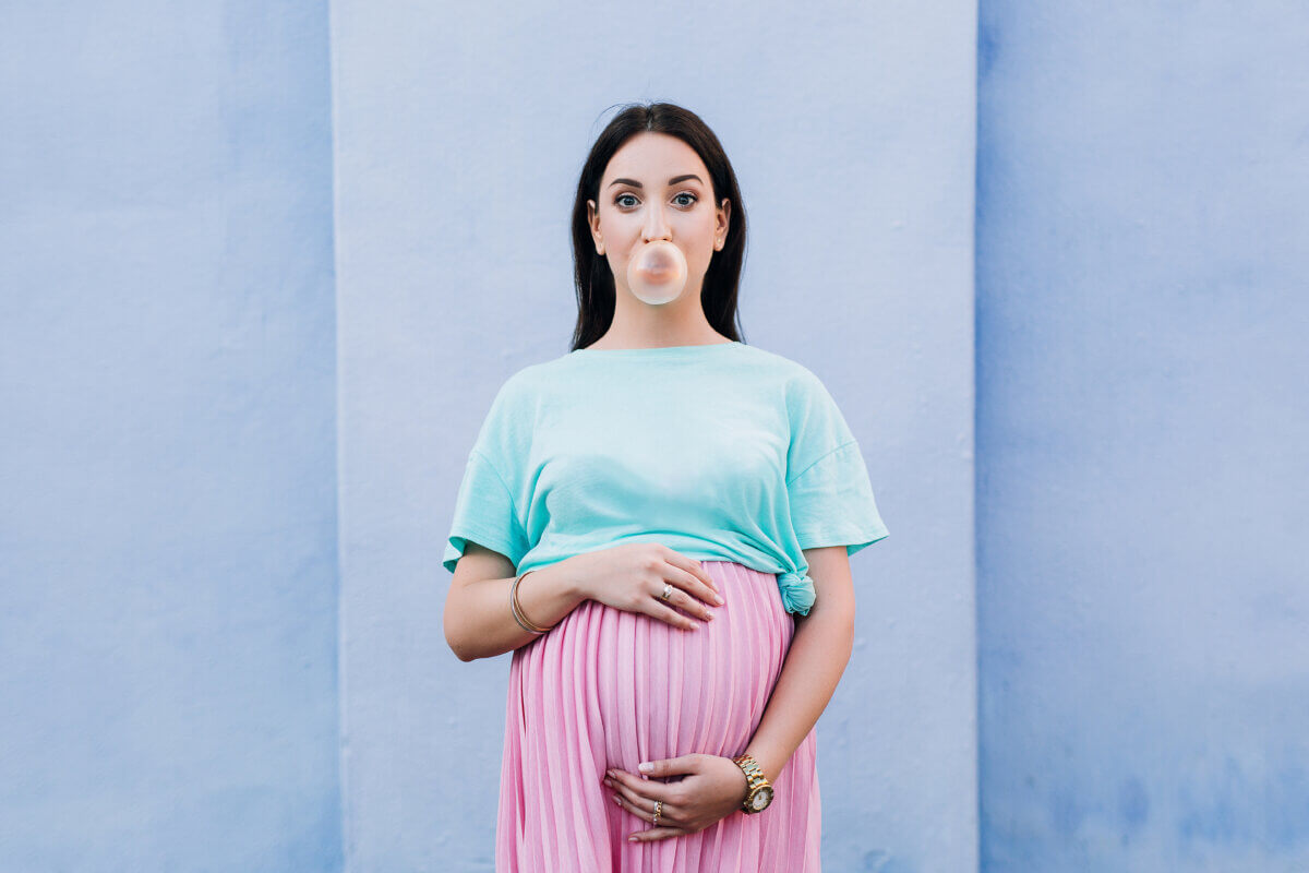 pregnant woman blows a bubble with gum