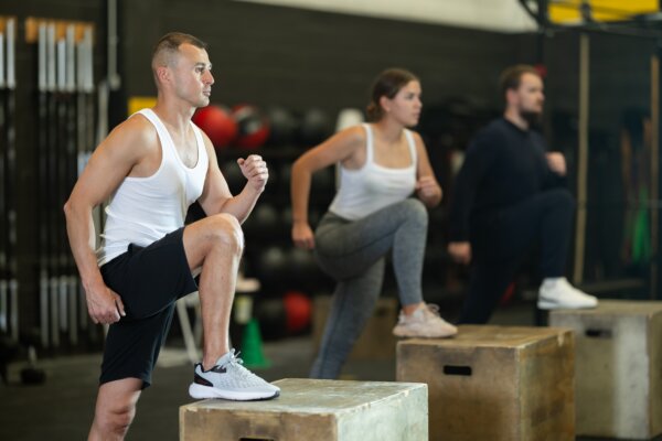Group doing box step-up exercise in CrossFit-style workout class.