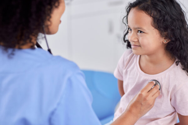 Doctor listening to little girl's heart
