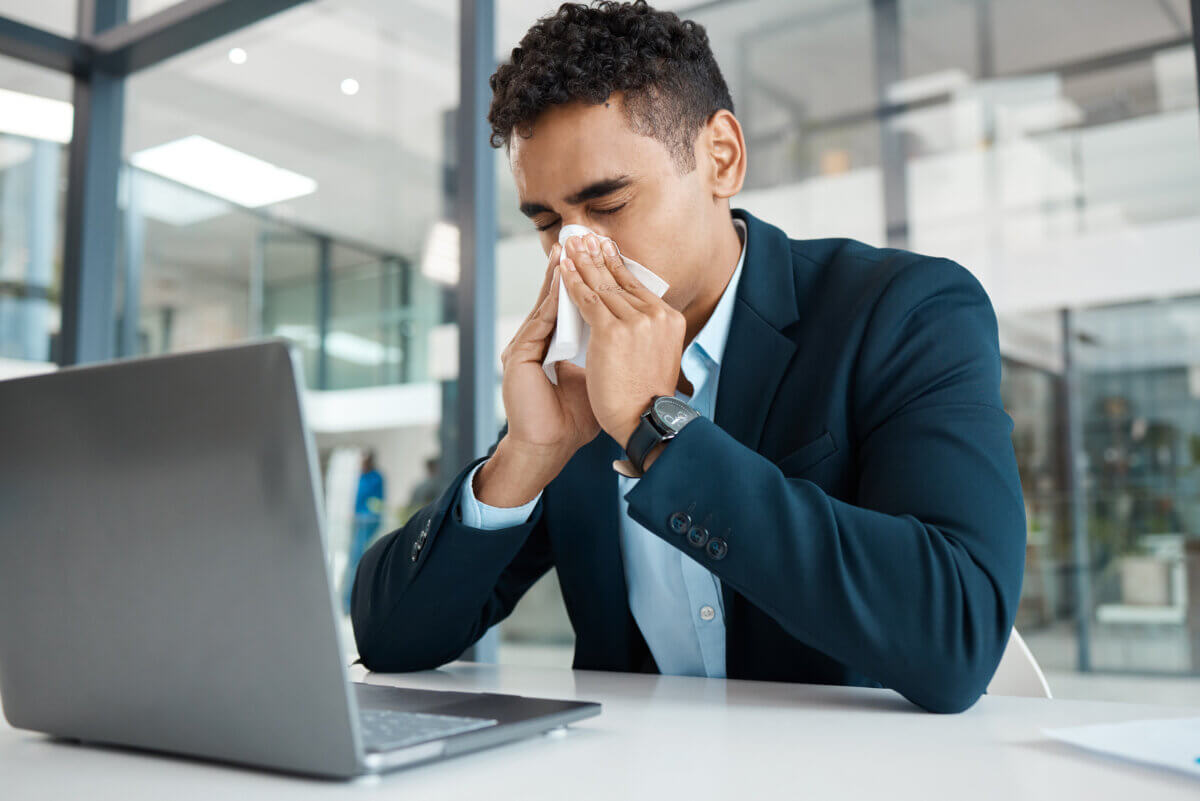 Sick worker blowing his nose in the office