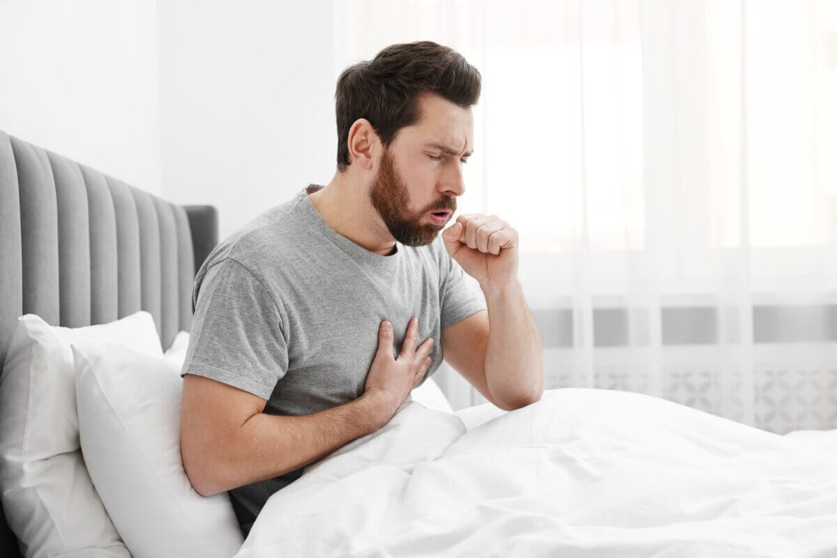 Sick man coughing in bed