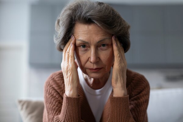 An older woman with her hands pressing on her temples