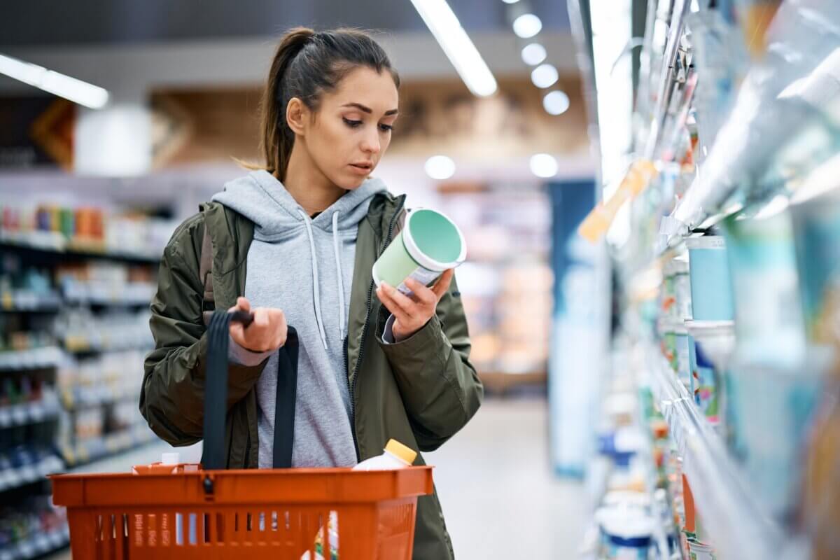 Woman shopping for yogurt at grocery store and reading food label