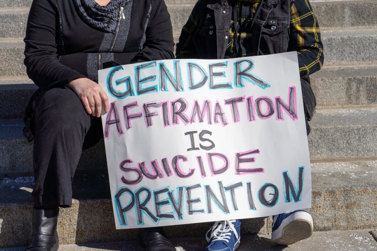 People holding flags and signs in support of transgender youth being able to receive gender, affirming care